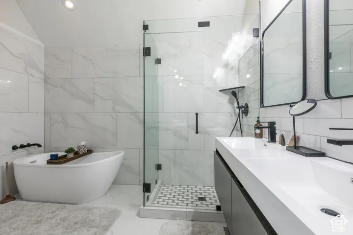 Freestanding soaking tub, frameless glass shower enclosure, dual basin vanity, large format wall tile, and recessed lighting