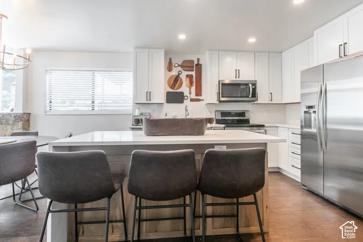 Kitchen featuring white shaker cabinetry, stainless steel appliances, a center island with a light-toned countertop, and recessed lighting