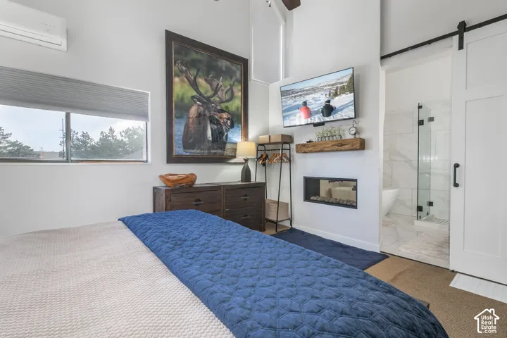 Recessed electric fireplace with a wood mantel, barn door entry, and tiled shower with glass enclosure