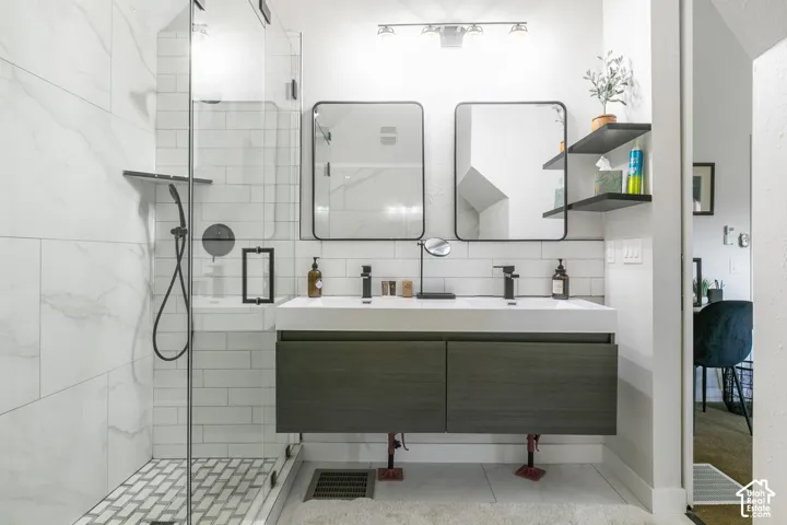 Glass-enclosed shower with white subway tile and herringbone mosaic floor