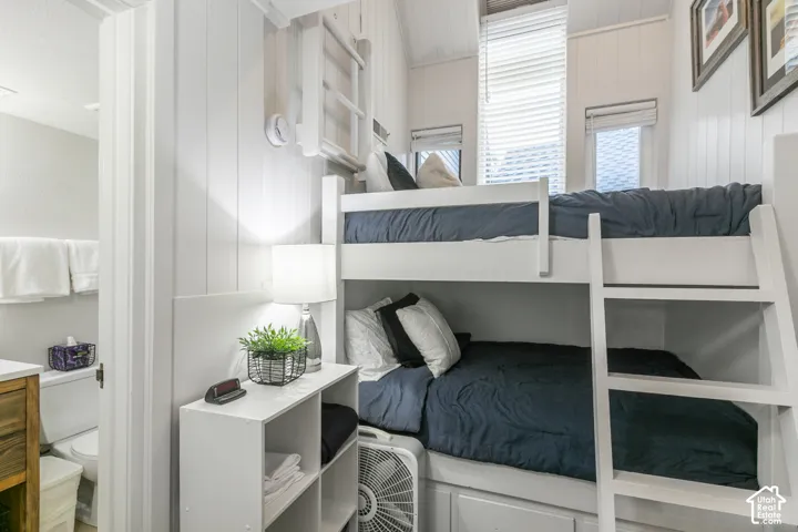 Built-in bunk beds with integrated storage, white vertical plank walls, white window blinds, and recessed lighting