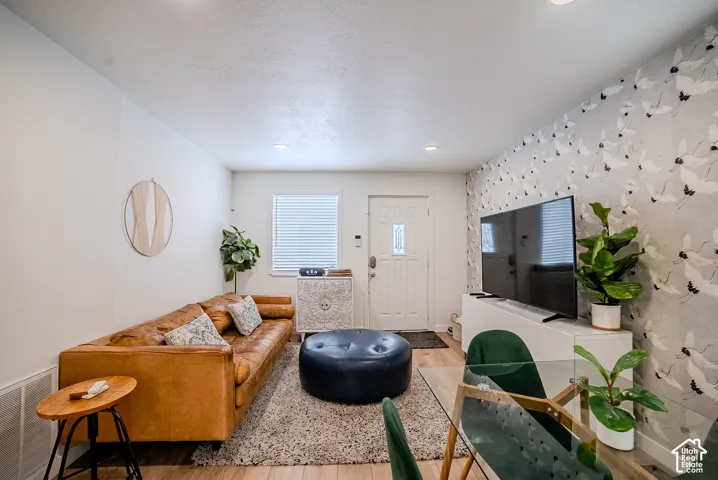 Living area featuring recessed lighting, wood-finish flooring, and a patterned accent wall