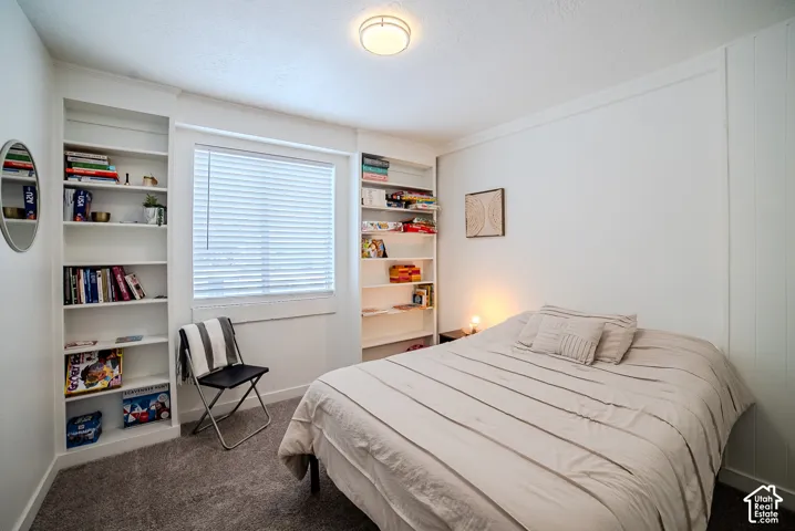 Built-in floor-to-ceiling shelving, neutral wall finishes, window with horizontal blinds, overhead dome lighting, and wall-mounted paneling