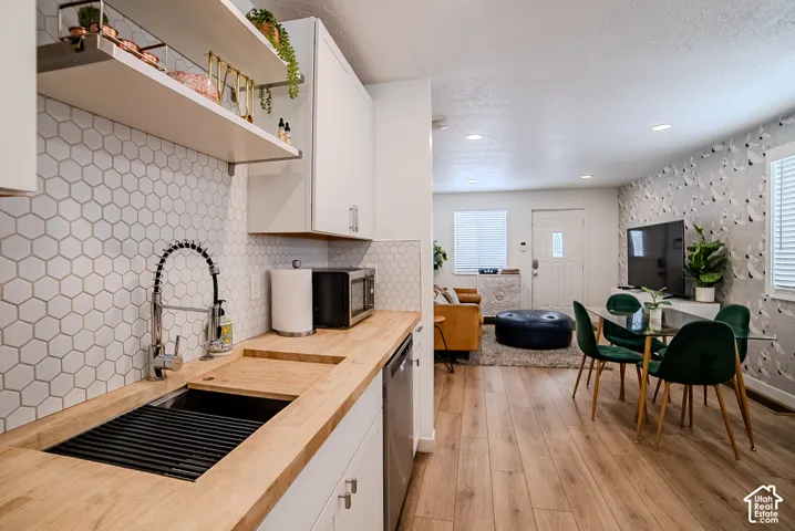 Kitchen featuring wood-finish countertops, white cabinetry, honeycomb-pattern backsplash, recessed lighting, and wood-finish flooring