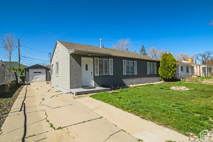 Single-story residence featuring a painted masonry exterior, shuttered windows, concrete driveway, and a detached single-car garage