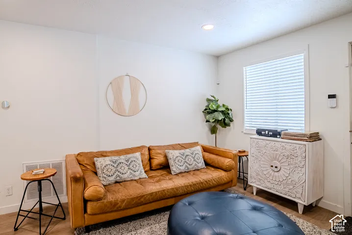 Room featuring wood-finish flooring, recessed lighting, and a window with horizontal blinds