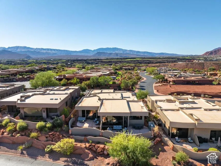 Stucco exterior architecture featuring flat rooflines, covered patios, and hardscaped desert landscaping with mature foliage, set against a backdrop of mountain scenery