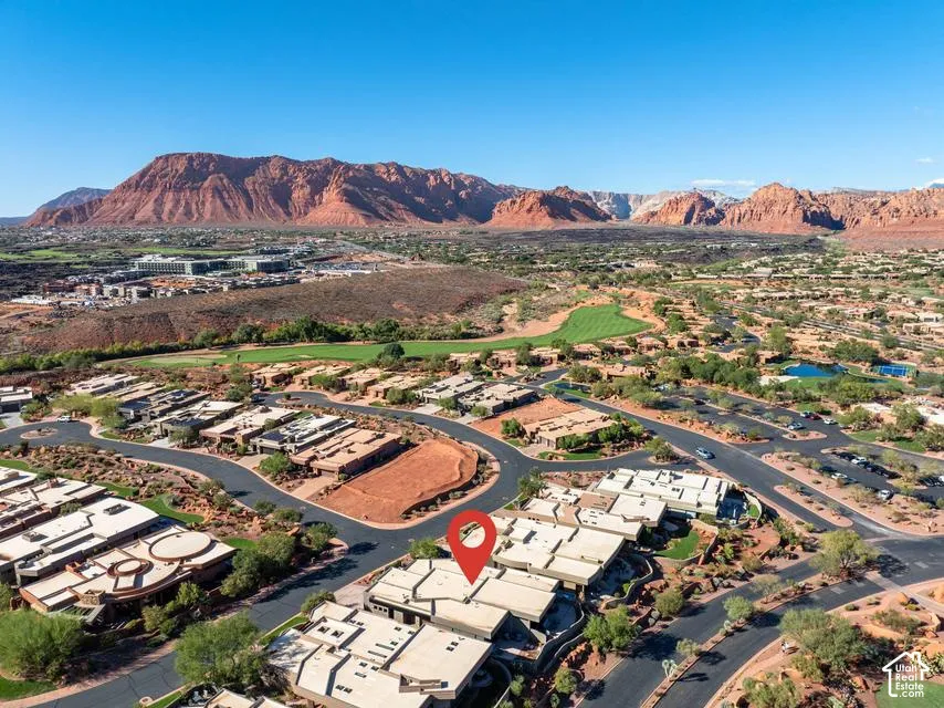 Aerial perspective featuring red rock mountain scenery, proximity to a golf course, and desert landscape integration within the community
