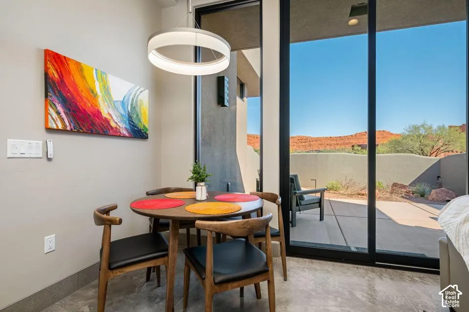 Floor-to-ceiling sliding glass door, polished concrete flooring, contemporary circular pendant light, and exterior patio featuring mountain scenery