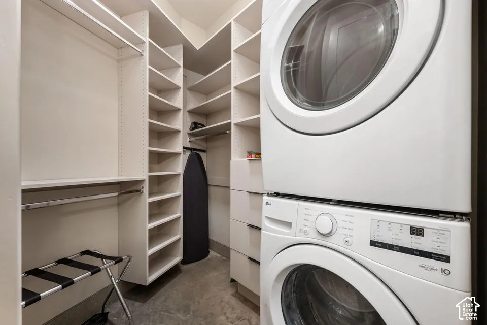 Custom built-in white shelving system featuring floor-to-ceiling storage, multiple drawers with dark hardware, integrated hanging rods, and a stacked front-loading laundry unit