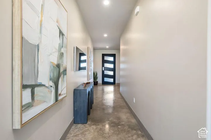 Entryway featuring polished concrete flooring, recessed lighting, and a dark-finished door with horizontal frosted glass panes