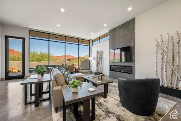 Living area featuring expansive floor-to-ceiling windows, polished concrete flooring, a floor-to-ceiling stone-tiled fireplace surround, and a linear built-in fireplace