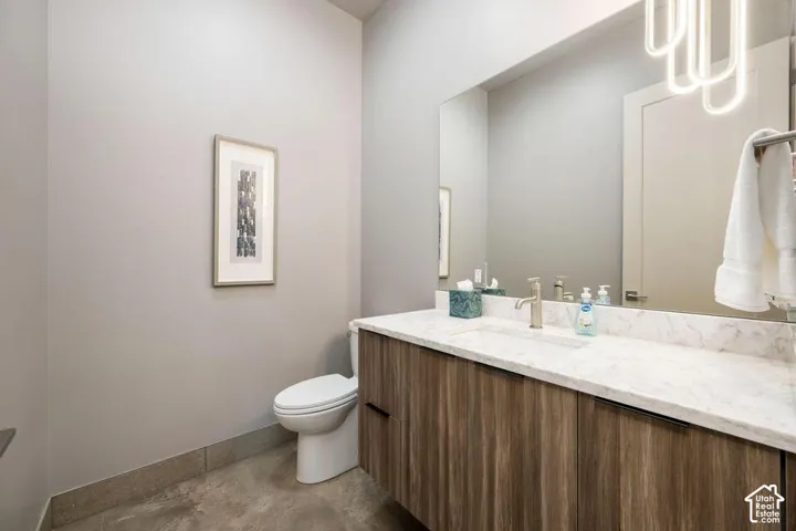 Floating vanity with wood-finish cabinetry, stone countertop with integrated basin, floor-to-ceiling mirror, and contemporary pendant lighting