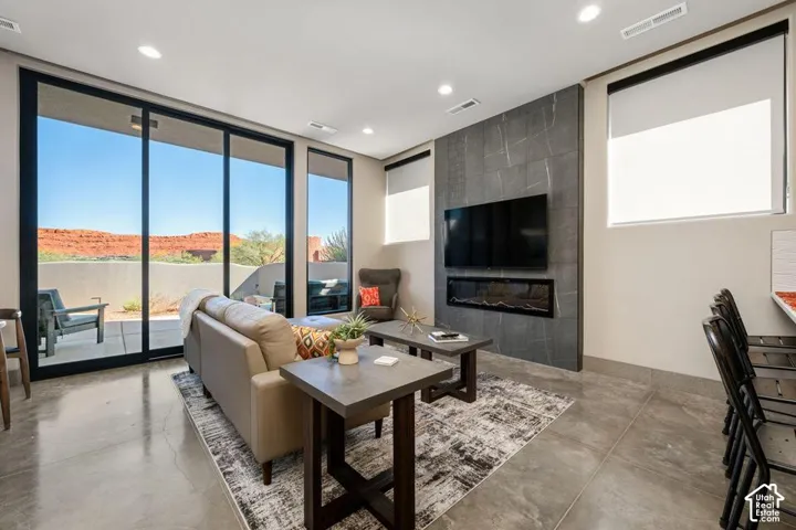 Living area featuring polished concrete flooring, recessed lighting, expansive glass sliding doors, and a full-height stone-finish fireplace surround with a linear electric insert