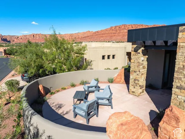 Curved concrete patio featuring stacked stone pillar accents, metal roof detailing, and mountain scenery