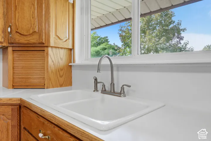 Kitchen featuring a white dual-basin sink, brushed metal pull-down faucet, solid-surface countertop, and wood-finish cabinetry with a built-in tambour appliance garage