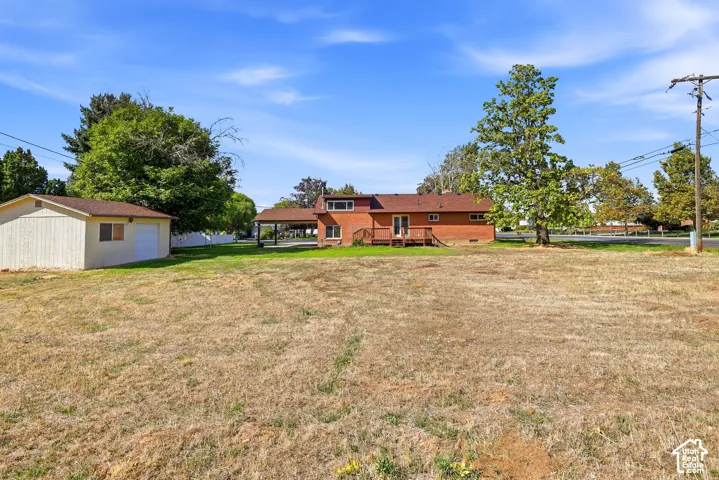 Expansive lot featuring a brick exterior, detached garage, and raised wooden deck