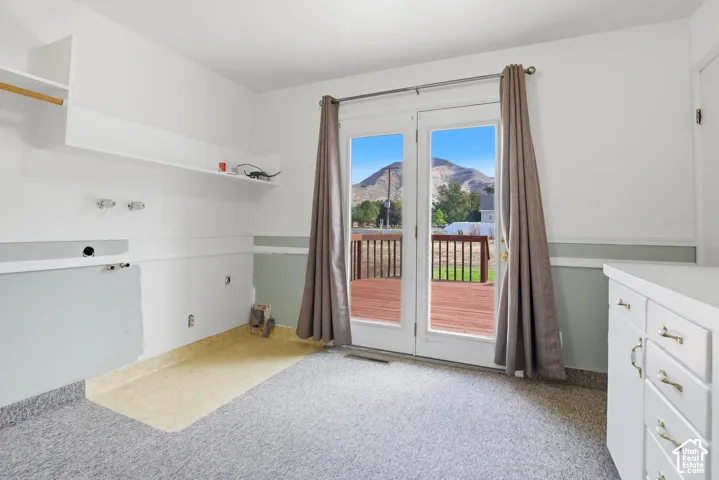 Room featuring built-in cabinetry, wall-mounted shelving, glass-paned double doors, and a mountain backdrop