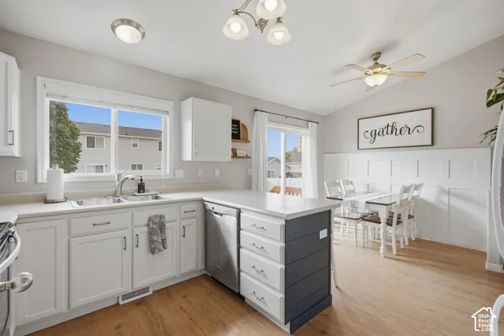 Kitchen featuring white shaker-style cabinetry, wood-finish flooring, stainless steel dishwasher, dual-basin stainless steel sink, and white wainscoting