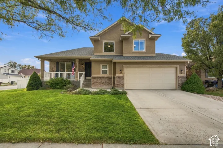Two-story exterior featuring a stone-veneer base, covered front porch with white railing, and a two-car attached garage