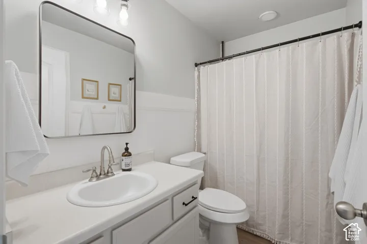 Vanity with a solid-surface countertop and integrated basin, metallic-finish hardware, rectangular wall-mounted mirror, and wall-paneling detailing