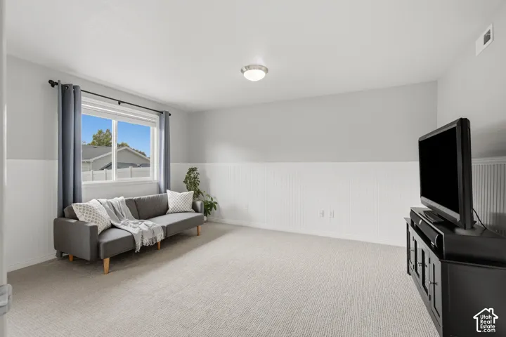 Interior room featuring white wainscoting, neutral carpeting, and a large horizontal sliding window