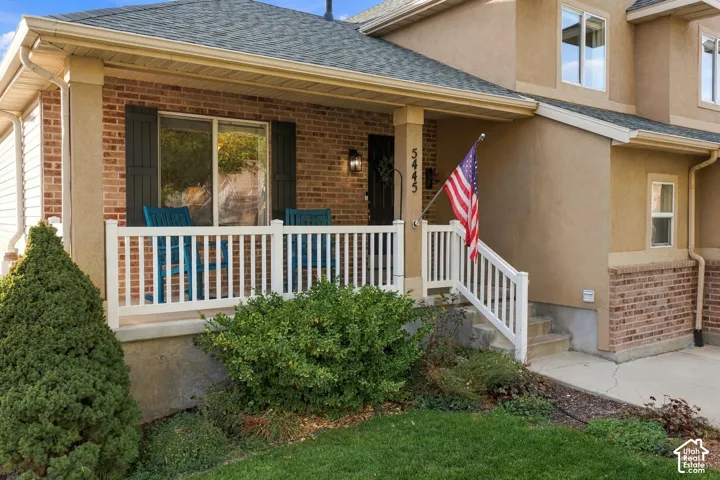 Exterior facade featuring a brick and stucco finish, a covered front porch with white railing, and architectural shingle roofing