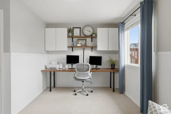 Built-in workspace featuring a wood-finish desk surface, white shaker-style wall cabinetry, open wood shelving, and white beadboard wainscoting