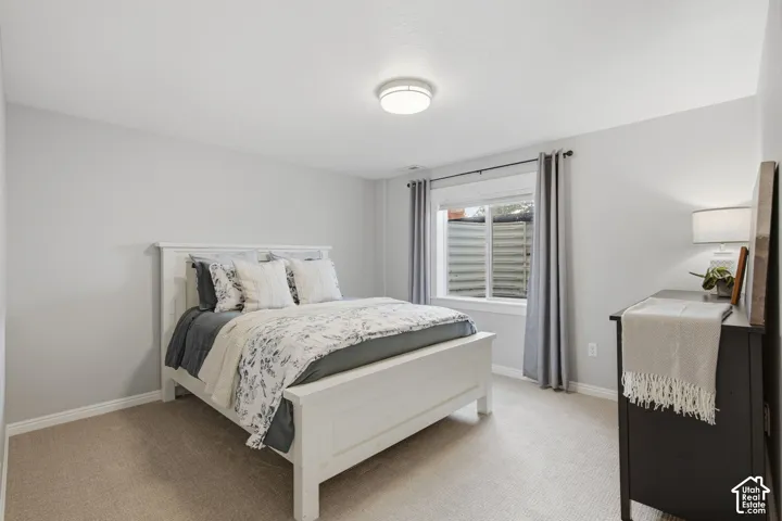 Neutral-toned bedroom featuring carpeting, a sliding window with a horizontal metal window well, and a flush-mount ceiling fixture