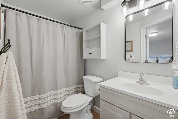 Bathroom featuring a vanity with a white countertop and oval under-mount sink, rounded-corner mirror, wall-mounted storage cabinetry, and a shower-tub combination