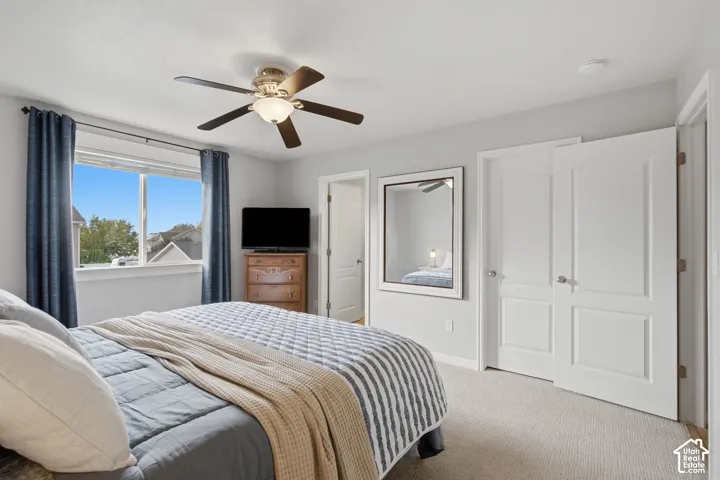 Neutral-toned room featuring neutral carpeting, a ceiling fan with integrated lighting, and multiple interior paneled doors