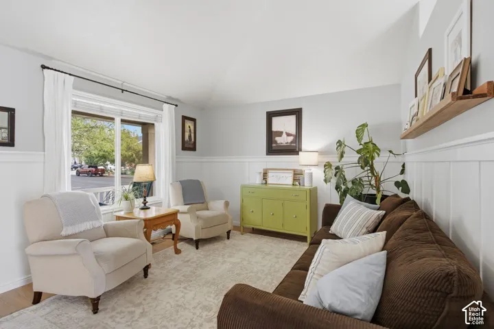 Vaulted ceiling, wall-to-wall wainscoting, large dual-pane window, and natural wood-finish wall shelving