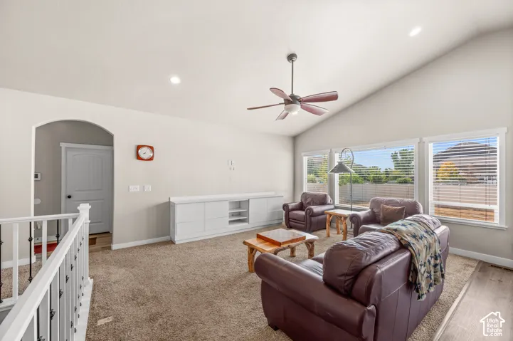 Vaulted ceiling with a central paddle fan, built-in white cabinetry, recessed lighting, and multiple windows