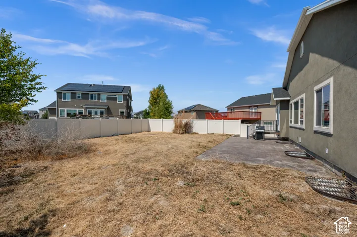 Fenced backyard featuring a concrete patio, stucco exterior, and ground-level window wells