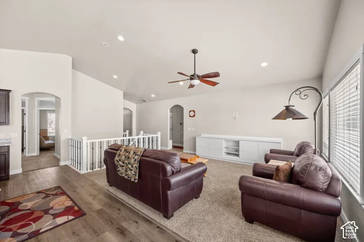 Vaulted ceilings featuring recessed lighting, a ceiling fan, built-in cabinetry, arched architectural details, and a combination of wood-finish flooring and wall-to-wall carpeting