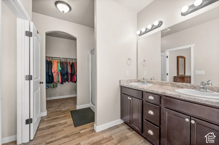 Bathroom featuring a double vanity with dark cabinetry, light-toned laminate countertops, dual drop-in sinks, and a full-width mirror