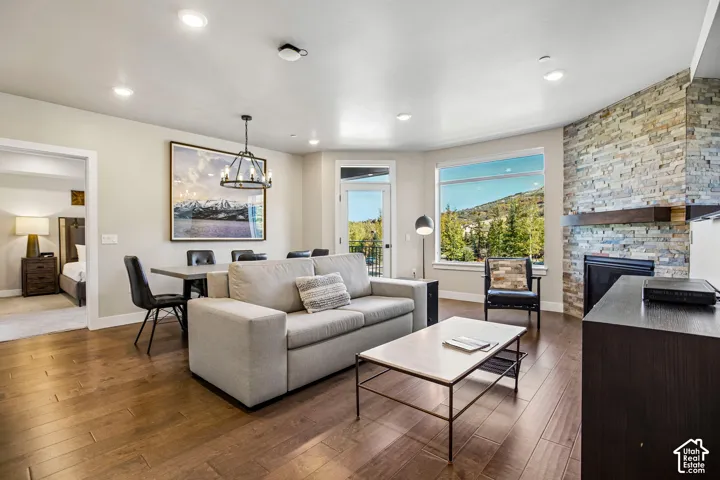 Living area featuring wood-finish flooring, floor-to-ceiling stone fireplace surround with a wood mantel, recessed lighting, and large windows with mountain scenery