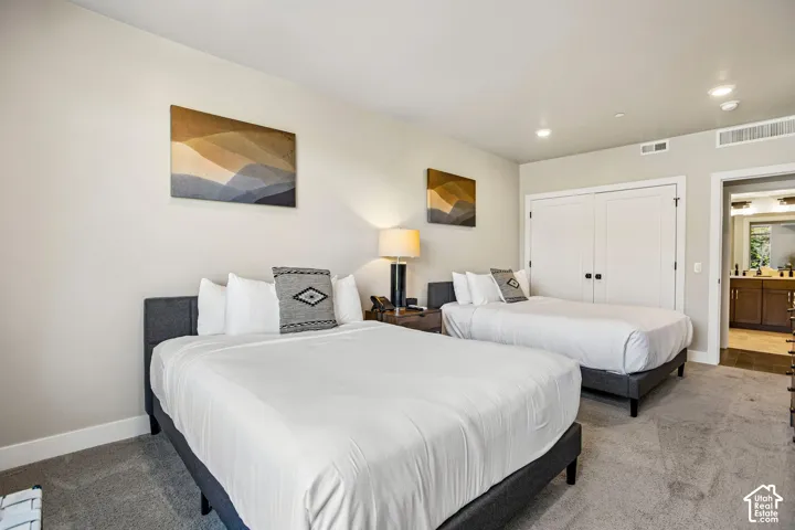 Neutral wall paint, plush carpeting, double-door closet with matte black hardware, and recessed lighting