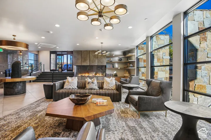 Large-scale floor-to-ceiling windows, natural stone accent walls, multi-arm modern light fixtures, integrated linear fireplace, and custom built-in shelving