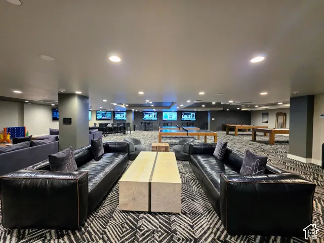 Spacious multipurpose room featuring patterned carpeting, recessed ceiling lighting, and structural columns