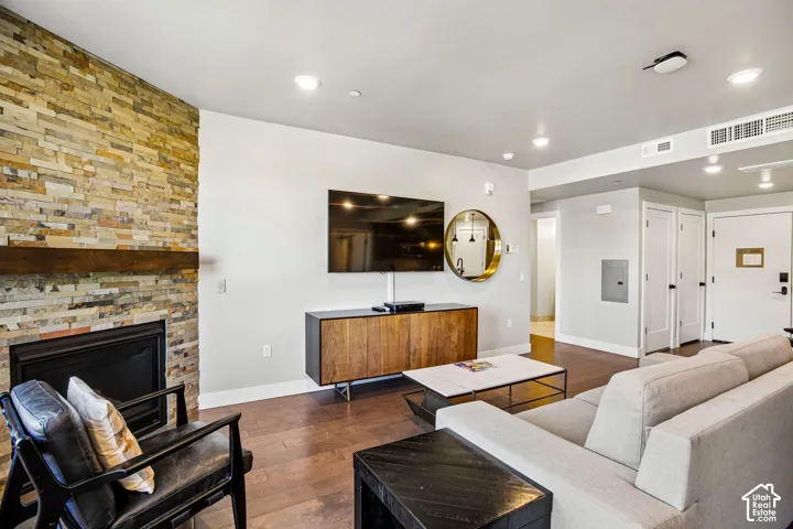 Fireplace featuring a multi-tonal stacked stone surround and a heavy wood mantel, paired with wood-finish flooring and recessed lighting