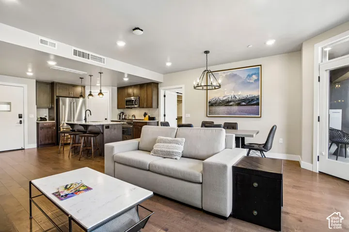 Open-concept interior featuring wood-finish flooring, recessed lighting, and a kitchen equipped with stainless steel appliances, a central island, and dark-toned cabinetry