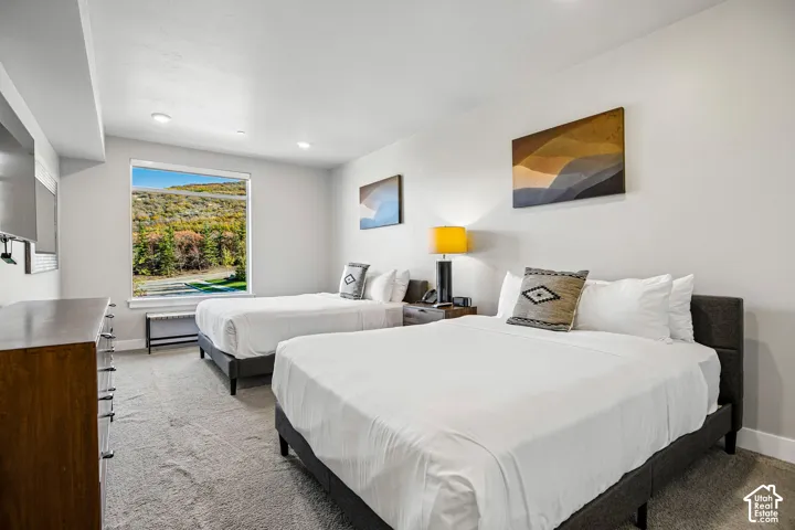 Neutral-toned carpeting, recessed ceiling lighting, and a large picture window showcasing mountainous terrain