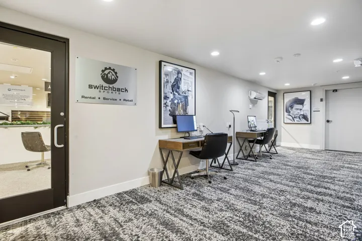 Commercial space featuring recessed ceiling lighting, patterned wall-to-wall carpeting, and a glass-paneled entry door with a metal handle