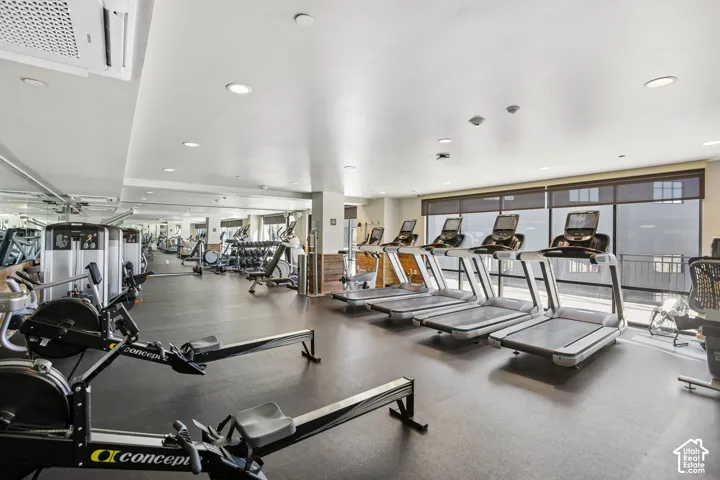 Fitness center featuring impact-resistant flooring, recessed lighting, and expansive windows with integrated roller shades