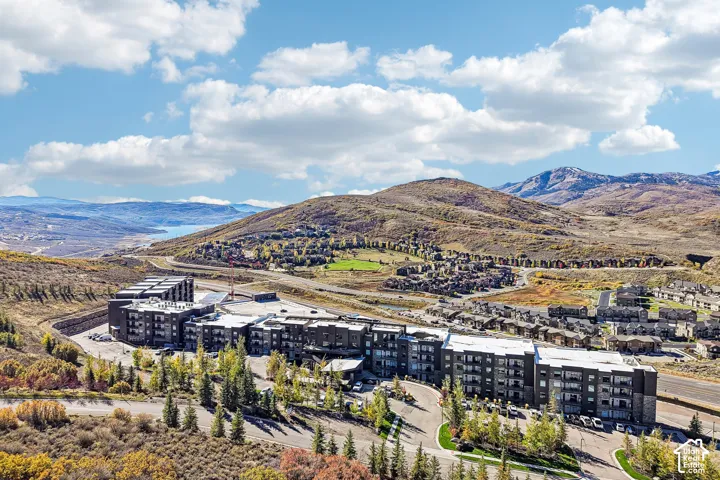 Aerial perspective of a multi-story residential complex featuring stone and siding exterior finishes, private balconies, and a mountain backdrop