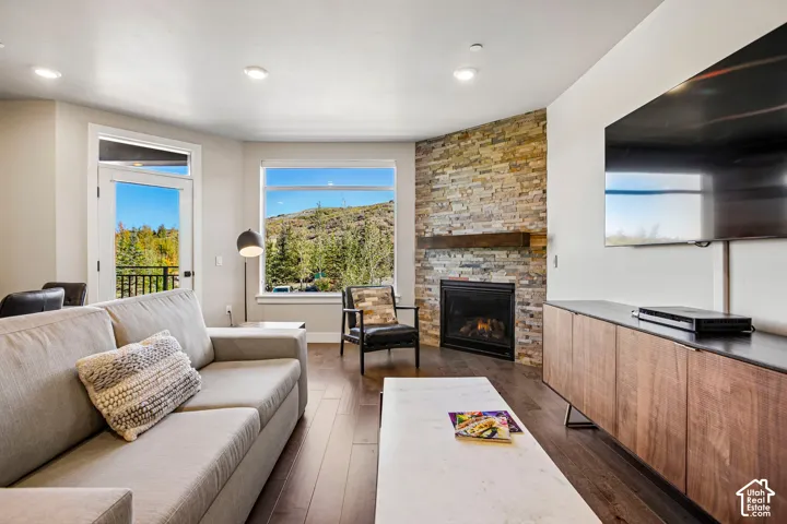 Living area featuring wood-finish flooring, recessed lighting, and a floor-to-ceiling stone fireplace with a thick timber mantel