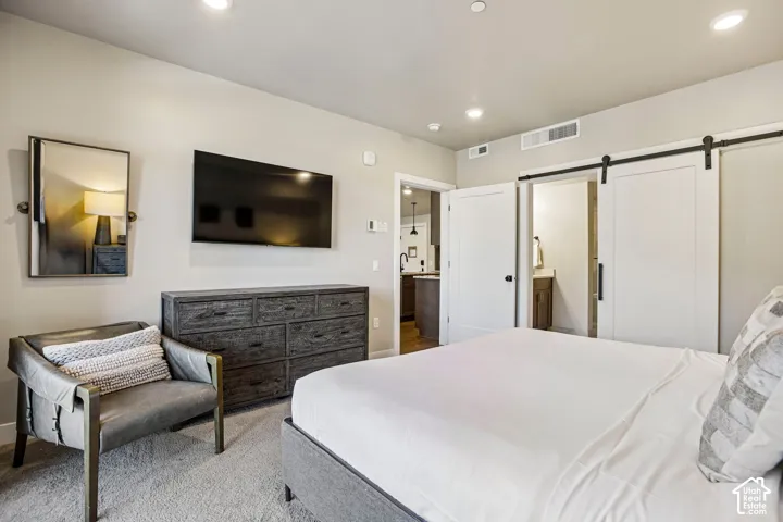Interior space featuring neutral wall paint, recessed lighting, carpeted flooring, and a sliding barn door with black hardware