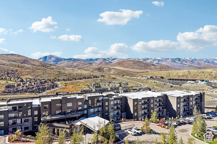 Multi-story residential complex featuring contemporary dark-toned exterior siding, stone masonry accents, covered porte-coch