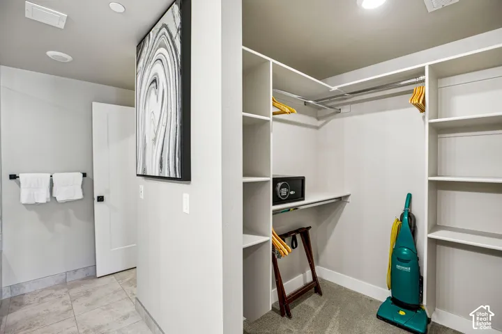 Walk-in closet featuring custom built-in white shelving, recessed lighting, and integrated garment rods